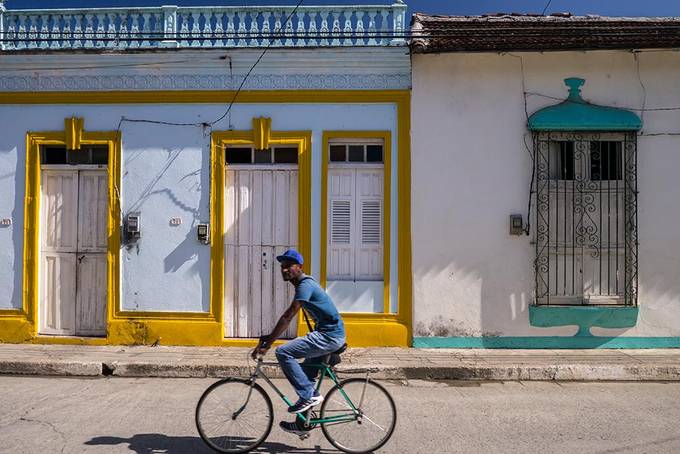 A cyclist riding passed some colourful buildings